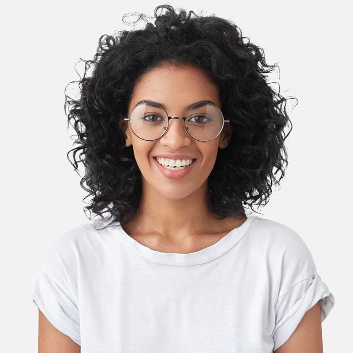 A woman with curly hair and glasses wearing a white t - shirt.