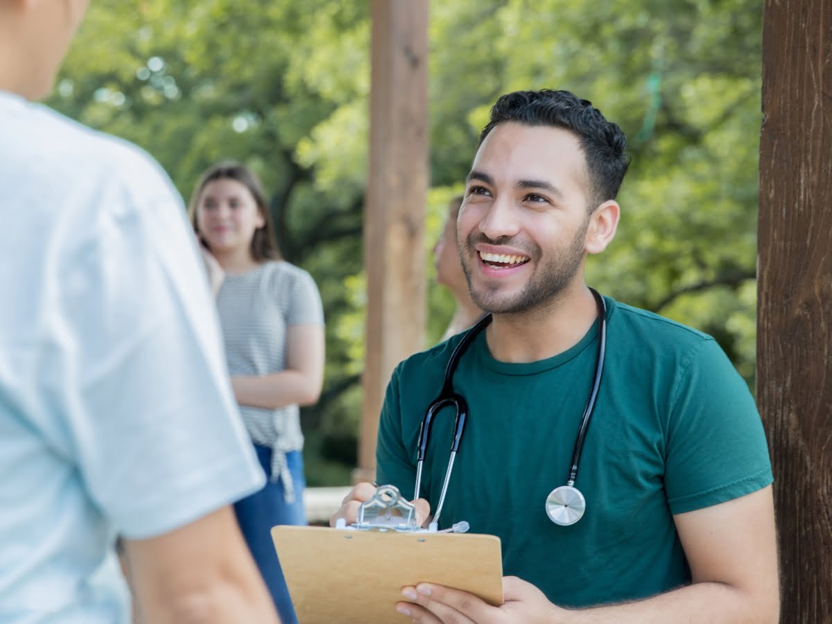 A stethoscope is shown on a clipboard in front of a man collaborating with partners.
