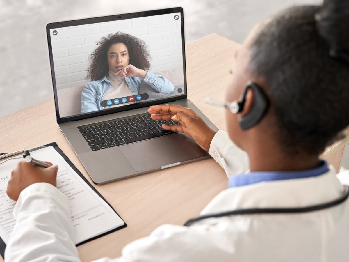 Partners, A woman is on a video call with a doctor on a laptop.