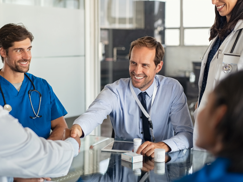 About Us: A group of doctors shaking hands at a table, demonstrating unity and collaboration.