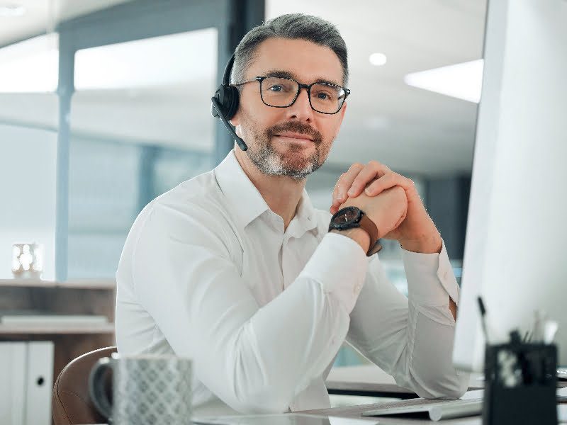 An insurance broker wearing glasses at a desk.